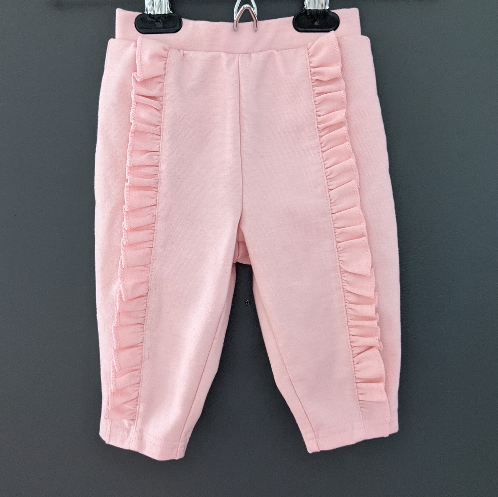 Baby pink sweatpants with ruffle detail on front.